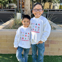 Two children wearing matching sweatshirts standing outdoors on a sunny day.